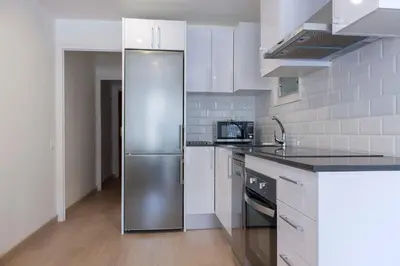 a stainless steel refrigerator in a kitchen with white cabinets at Flateli Roger 6 in Barcelona