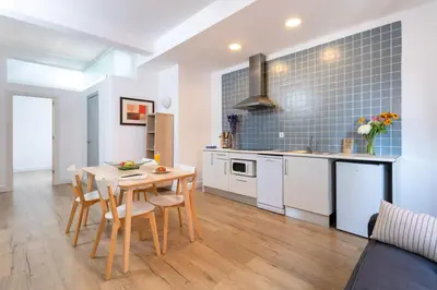 a kitchen with white cabinets and a table and chairs at Mayerling Bisbe Urquinaona in Barcelona