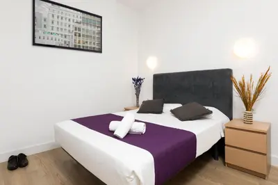 a bedroom with a large white bed with purple sheets and pillows at Mayerling Bisbe Urquinaona in Barcelona