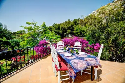 a table and chairs on a balcony with flowers at Can Ferran by Hello Homes Sitges in Sitges