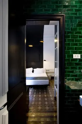 a bedroom with a bed and a green brick wall at Praktik Rambla in Barcelona
