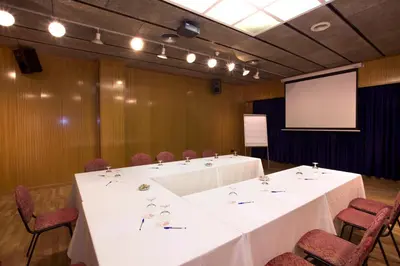a conference room with tables and chairs and a screen at Hotel Domo in Vilafranca del Penedès