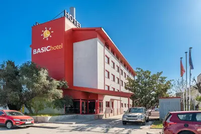 a red and white building with cars parked in a parking lot at Hotel Basic in Vilafranca del Penedès