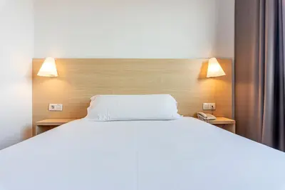 a bedroom with a white bed and two lamps at Hotel Basic in Vilafranca del Penedès