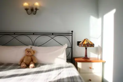 a teddy bear sitting on a bed next to a lamp at Privat Hotel Liberty Sitges in Sitges