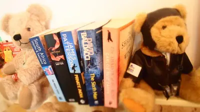 two stuffed teddy bears are holding books on a shelf at Privat Hotel Liberty Sitges in Sitges