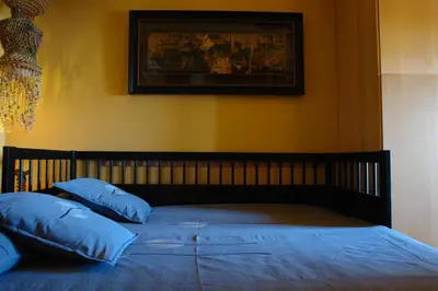 a bed with blue pillows and a picture on the wall at Sitges Beach Loft in Sitges