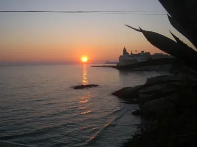 a sunset over the ocean with a castle in the distance at Sitges Beach Loft in Sitges