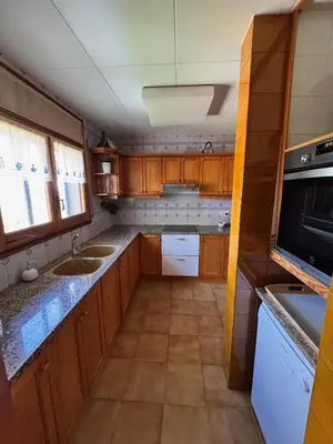 a small kitchen with wooden cabinets and a sink at Finca La Pedrera in Capellades