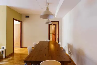 a dining room with a wooden table and white chairs at Comfortable 4 rooms 2Bath w balcony in Barcelona