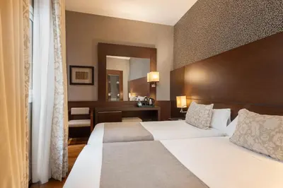 a hotel room with two beds and a mirror at Barcelona Hotel Colonial in Barcelona