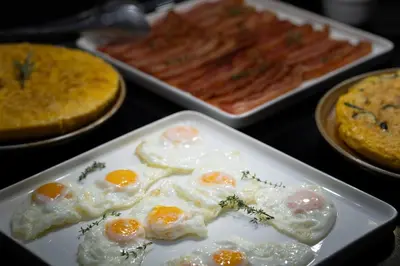a plate of eggs on a table with other foods at Barcelona Hotel Colonial in Barcelona
