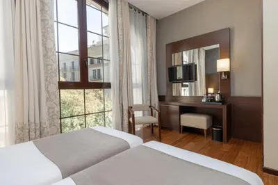 a hotel room with two beds and a desk and a window at Barcelona Hotel Colonial in Barcelona