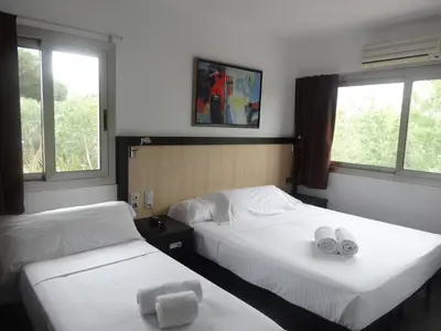 a hotel room with two beds and two windows at Hotel 170 in Castelldefels