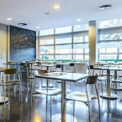 a restaurant with tables and chairs and a chalkboard at Hotel Air Penedès in Vilafranca del Penedès