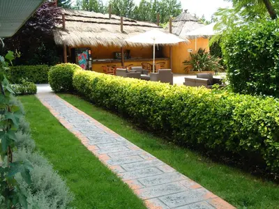 a garden with a path with chairs and an umbrella at Hotel Air Penedès in Vilafranca del Penedès