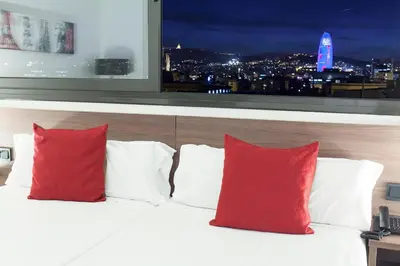 a white bed with red pillows and a window at Hotel Best 4 Barcelona in Barcelona