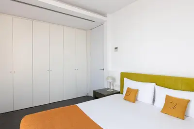 a bedroom with white cabinets and a bed with orange pillows at Cosmo Apartments Sants in Barcelona