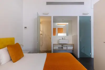 a bedroom with a white bed with an orange pillow at Cosmo Apartments Sants in Barcelona