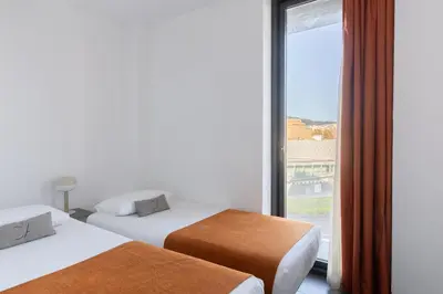 two beds in a room with a large window at Cosmo Apartments Sants in Barcelona