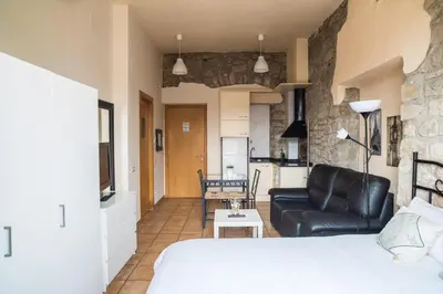 a bedroom with a bed and a living room with a couch at Urbi Apartments in Manresa