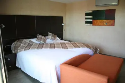 a bedroom with a large bed and a orange chair at Montaltmar in Sant Vicenç de Montalt