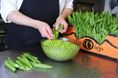a person cutting up green peas in a bowl at Montaltmar in Sant Vicenç de Montalt