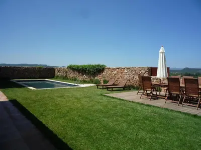 a lawn with chairs and an umbrella and a pool at Can Gramunt in La Torre de Claramunt