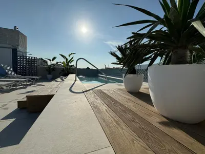 a balcony with palm trees and a swimming pool at Alenti Sitges Hotel in Sitges