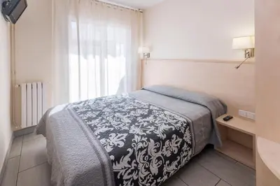 a bedroom with a bed with a black and white blanket at Hostal Solimar in Badalona