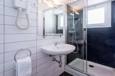 a white bathroom with a sink and a shower at Hostal Solimar in Badalona