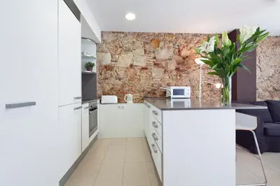 a kitchen with white cabinets and a brick wall at Inside Barcelona Apartments Sants in Barcelona