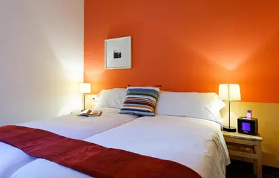 a bedroom with an orange wall and a large bed at Inside Barcelona Apartments Esparteria in Barcelona