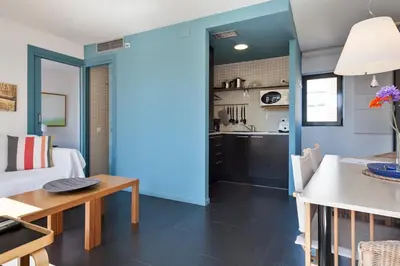 a kitchen and living room with blue walls and a table at Inside Barcelona Apartments Esparteria in Barcelona