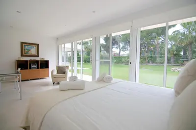 a large white bedroom with a large bed and windows at Luxury Beach House in Sitges