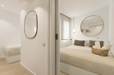 a white bedroom with a bed and a mirror at Ola Living Santa Anna in Barcelona