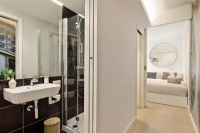 a bathroom with a sink and a shower and a bed at Ola Living Santa Anna in Barcelona