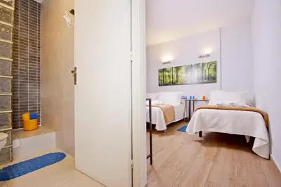 a bathroom with two beds and a shower in a room at Barcelona City Hotel in Barcelona