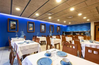a restaurant with white tables and chairs and blue walls at Bed and Breakfast El Pekinaire in Calella