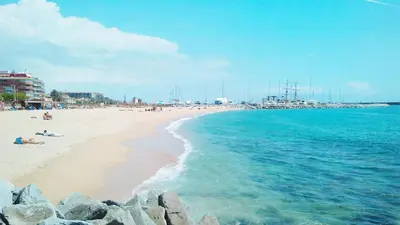 a beach with people laying on the sand and the water at Vila De Premiá in Premiá de Mar