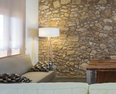 a living room with a couch and a stone wall at Apartament Major 33 in Arbós