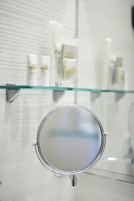 a glass shelf with a mirror and toiletries on it at Hostemplo Sagrada Familia in Barcelona