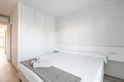 a white bedroom with a bed with a towel on it at Tango in Sitges