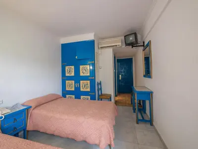 a bedroom with two beds and a blue cabinet at Checkin Garbí in Calella