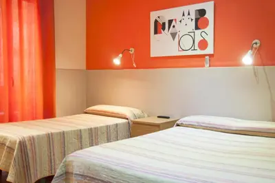 two beds in a room with orange walls at Be Ramblas Guest House in Barcelona