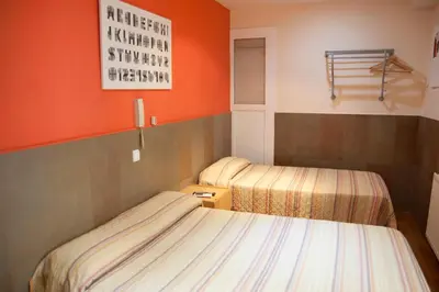 two beds in a small room with orange walls at Be Ramblas Guest House in Barcelona