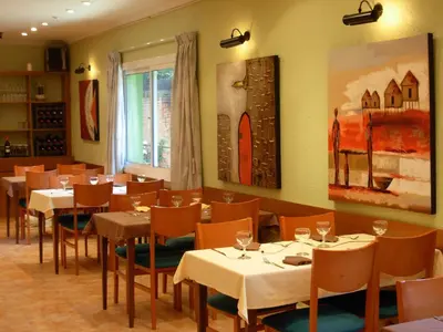 a restaurant with tables and chairs and a painting on the wall at Hotel Rodsan Suizo in Castelldefels