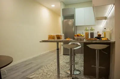 a kitchen with a counter with a refrigerator and stools at Barcelona City Ramblas in Barcelona