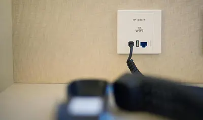 a charging cable plugged into a lightswitch on a wall at Sono House in La Garriga
