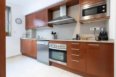 a kitchen with wooden cabinets and a stove and microwave at Barcelona - Camp Nou in Hospitalet de Llobregat